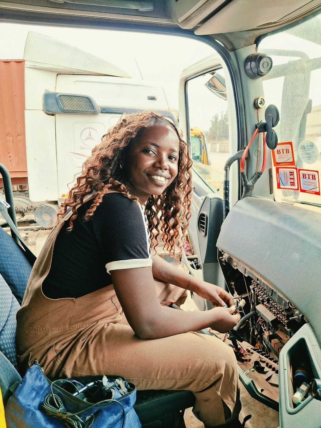 Shenitech technician smiling inside a truck cab while wiring vehicle electronics on the dashboard